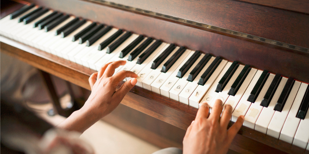 Cropped image of woman playing piano. Female is practicing on musical instrument. She is at home.